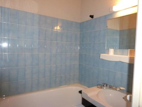 uma casa de banho em azulejos azuis com uma banheira e um lavatório em ZENITH 2017 em Le Sauze