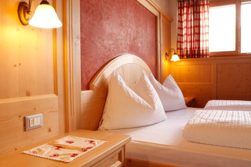 a bedroom with a bed with white pillows on it at Garnì Iosc in San Vigilio Di Marebbe