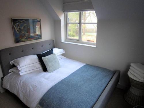 a bedroom with a bed with white sheets and a window at Crown Cottage, Orford - Prime Orford Location in Orford