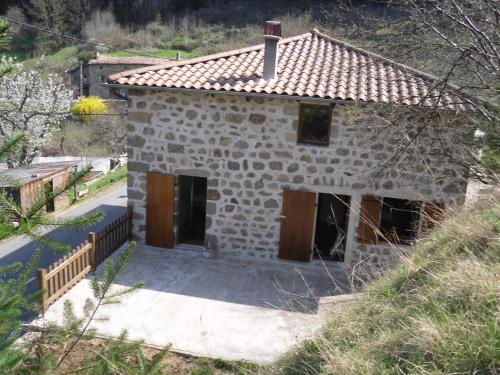 a small stone house with brown doors on a hill at Gîte-La Combelle in Dornas