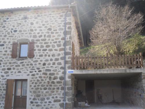 a man sitting next to a building with a balcony at Gîte-La Combelle in Dornas