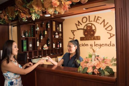 two women standing at a bar in front of a mirror at Hostal La Molienda in Puyo