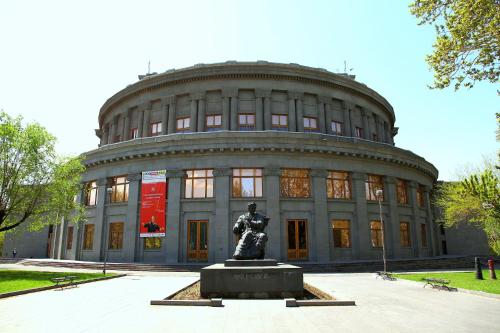 a large building with a statue in front of it at Imperial Palace Hotel Yerevan in Yerevan
