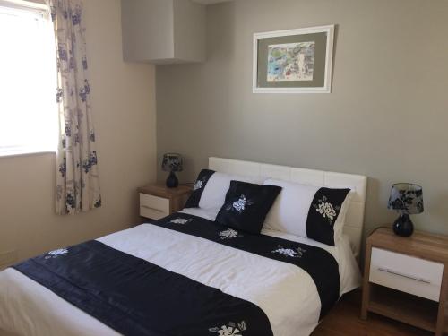 a bedroom with a bed with black and white pillows at Towan Beach Holiday Flat in Newquay