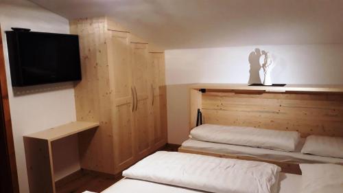 a room with two beds and a flat screen tv at Pension Sprenger in San Valentino alla Muta