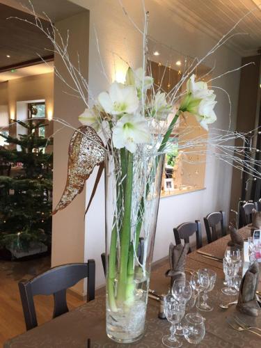a vase filled with water and white flowers on a table at Hotel Restaurant Beau Séjour in Morsbronn-les-Bains
