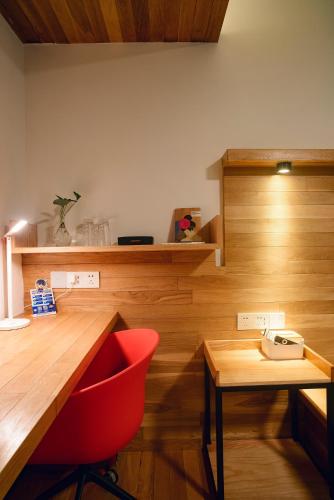 a red chair sitting next to a wooden desk at Rock&Wood Cozy House in Hangzhou