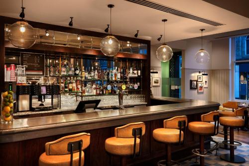a bar with brown stools in a restaurant at Leonardo Hotel Cardiff in Cardiff
