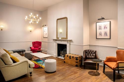 a living room with furniture and a mirror at Leonardo Hotel Cardiff in Cardiff