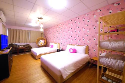 a bedroom with two beds and a pink wall at Traveler Station in Kaohsiung