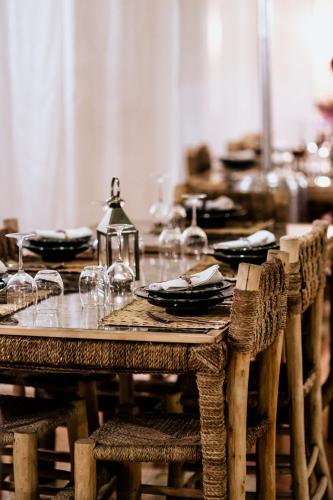 a wooden table with plates and wine glasses on it at L'Ma Lodge in Skoura