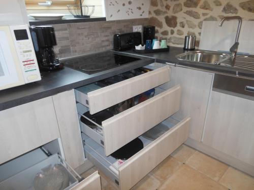 - une cuisine avec des tiroirs blancs et un évier dans l'établissement Le Jardin à Mordreuc, à Pleudihen