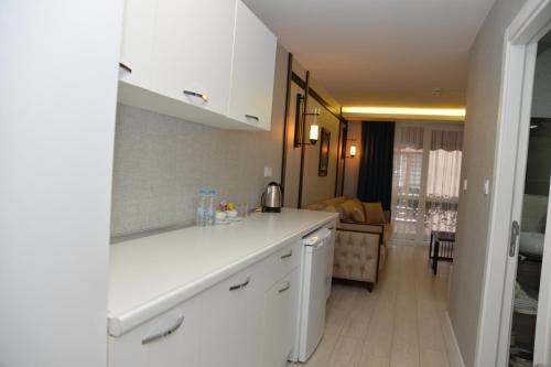 a kitchen with white cabinets and a living room at Gardenya Suite Hotel in Trabzon