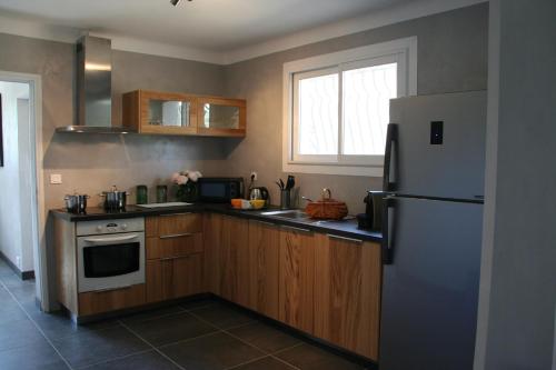 une cuisine avec des armoires en bois et un réfrigérateur dans l'établissement Maison Loubiere, à Pignans