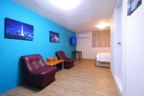 a room with a couch and a chair and a bed at Traveler Station in Kaohsiung