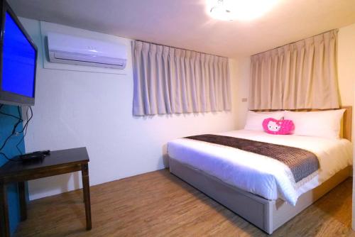 a bedroom with a bed with a pink bag on it at Traveler Station in Kaohsiung