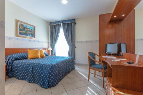 a bedroom with a bed and a desk with a computer at Hotel Traiano in Civitavecchia