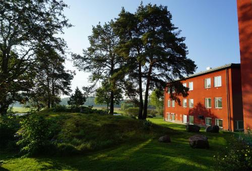 ein orangefarbenes Gebäude auf einem grasbewachsenen Hügel neben Bäumen in der Unterkunft Runö Möten & Events in Åkersberga