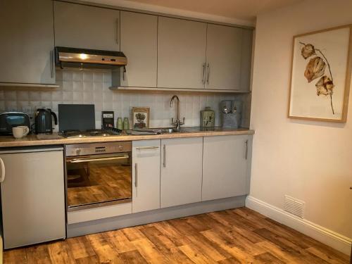 een keuken met witte kasten en een houten vloer bij Flat 4, York Terrace in Norwich