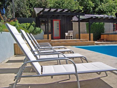 a row of lounge chairs sitting next to a pool at Waiorau Homestead in Cardrona
