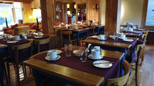 un restaurante con mesas de madera y sillas con platos en Hosteria El Establo, en Villa La Angostura