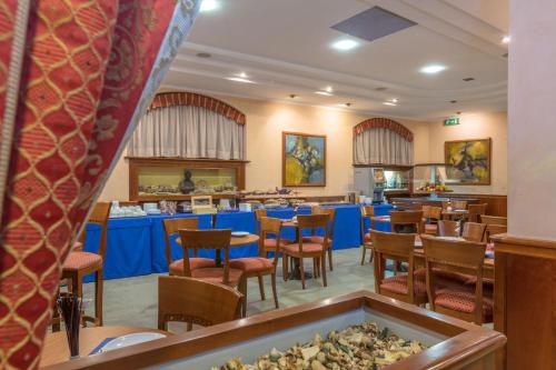 uma sala de jantar com mesas e cadeiras num restaurante em Hotel Traiano em Civitavecchia