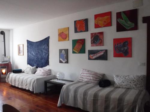 a living room with two beds and paintings on the wall at Stasion Di Pueste in Nogaredo Al Torre