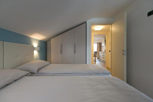 1 dormitorio con 1 cama blanca grande y cabecero en Appartamenti Guana, en Livigno
