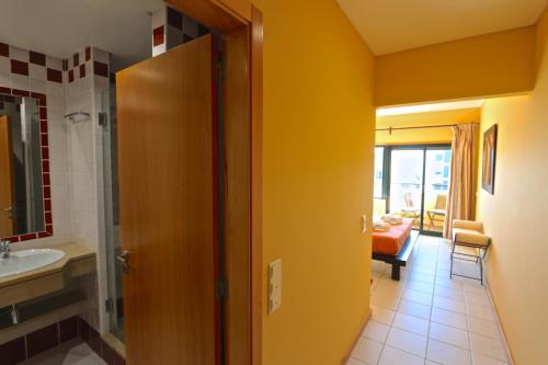 La salle de bains est pourvue d'un lavabo et d'une porte menant à une chambre. dans l'établissement Terraços de Vilamoura 55- Clever Details, à Vilamoura