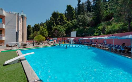 une grande piscine bleue avec des tables et des chaises dans l'établissement Hotel New York, à Vlorë