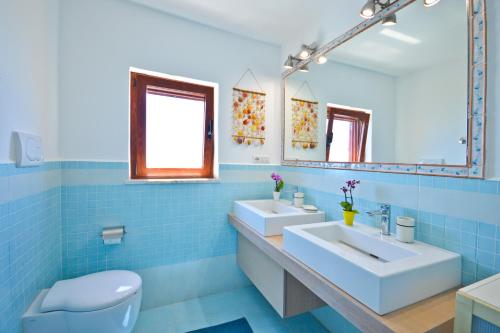 a blue tiled bathroom with two sinks and a toilet at Villa Azzurra in Conca dei Marini