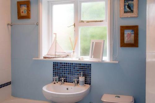 a bathroom with a sink and a window with a boat on it at Castle Cottage Orford in Orford