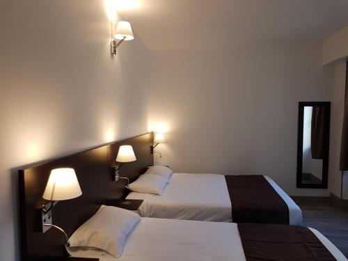 two beds in a hotel room with two lamps at Nevers Hotel in Nevers
