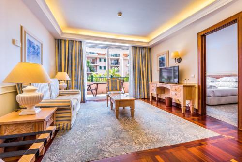 a living room with a couch and a tv at Pestana Royal All Inclusive Ocean & Spa Resort in Funchal