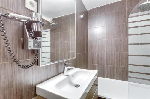 a bathroom with a sink and a hair dryer on the wall at Hotel Opera Maintenon in Paris