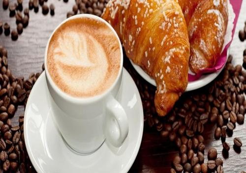 a cup of coffee and a plate of pastries and coffee beans at Argo Apartments in Kato Daratso