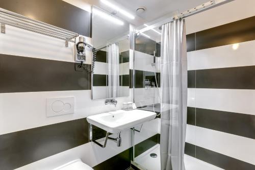 a white bathroom with a sink and a shower at Hotel Opera Maintenon in Paris