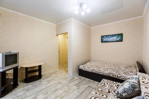 アストラハンにあるАпартаменты на Космонавтов 18のベッド2台とテレビが備わる小さな客室です。