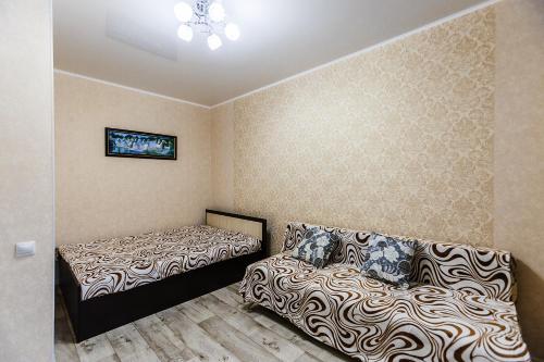 アストラハンにあるАпартаменты на Космонавтов 18のベッド2台とソファが備わる客室です。