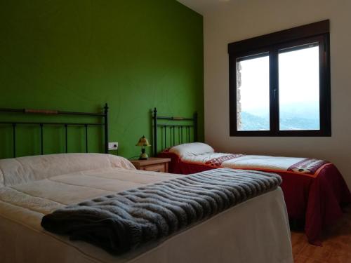 2 camas en una habitación con paredes verdes y ventana en Piedra del Tesoro, en Riópar