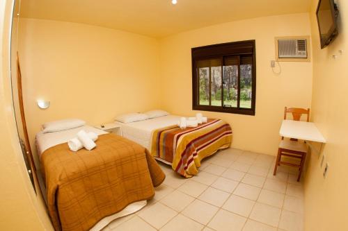 a hotel room with two beds and a window at Pousada Pedra Bonita in Cristal