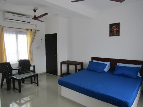a bedroom with a blue bed and a chair at Queens Park Apartments in Colombo
