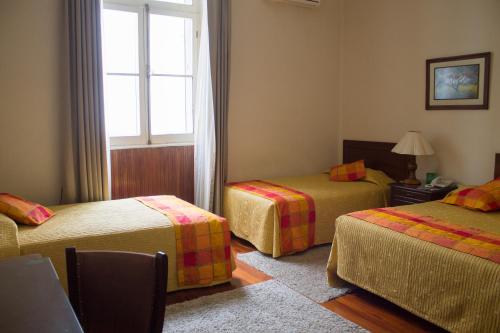 a room with three beds and a window at Hotel Victoria Plaza in Tarija