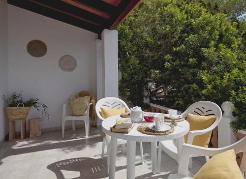 Viviendas Los Olivos - Formentera Break في بلايا ميجورن: طاولة بيضاء وكراسي على الفناء