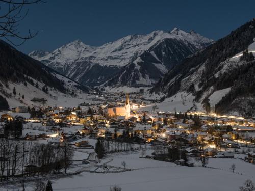 a town in the snow at night with a mountain at Appartement-Pension Fahrnberggut in Rauris