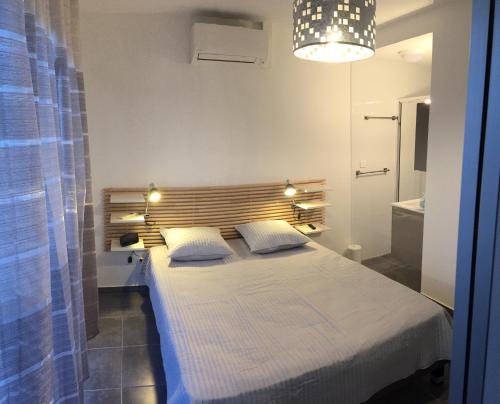 una camera da letto con un letto grande con testiera in legno di Maison Le Jean Bart a Cap d'Agde