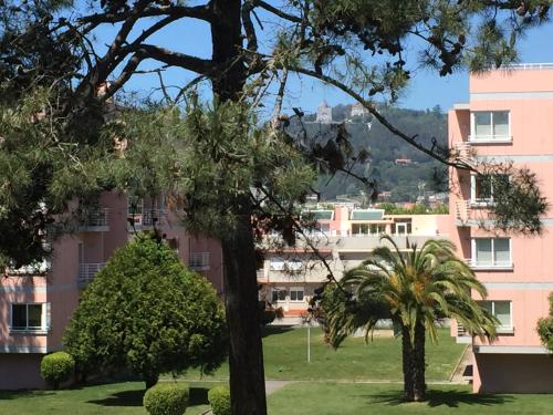 a pink building with trees in front of it at Viana do Castelo, Cabedelo Beach Apartment in Viana do Castelo