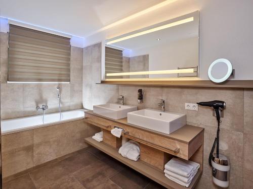 a bathroom with two sinks and a mirror and a tub at A-VITA Viktoria & A-VITA living luxury apartments in Seefeld in Tirol