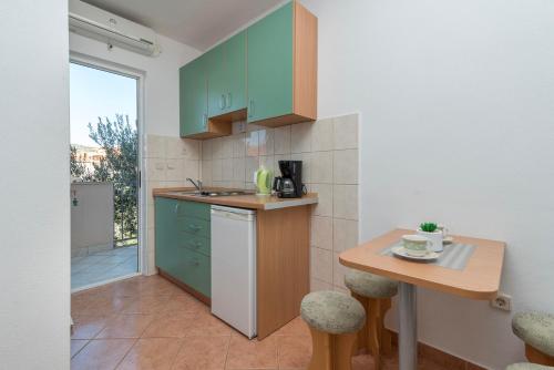 una cucina con armadi verdi e un tavolino di Apartments Ivana-Gustirna a Gustirna