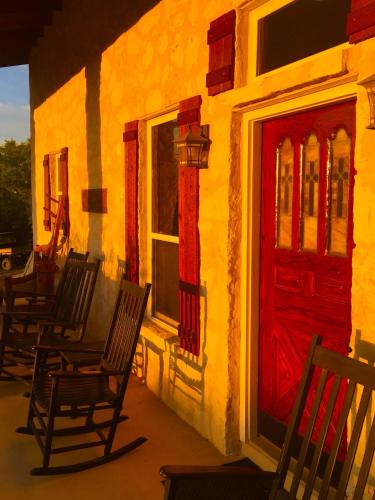 a group of chairs sitting outside of a building with a red door at Glory Hills Ranch in Pipe Creek